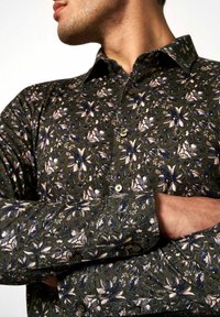 Hemd mit Knopfleiste aus dunkelgrünem Stoff mit floralem Muster in Pink und Marineblau, strukturiertes Material und grünen Knöpfen.
