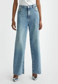 Light wash denim wide-leg jeans featuring a high waist, front pockets, and a straight silhouette. Distinctive stitching along the seams.