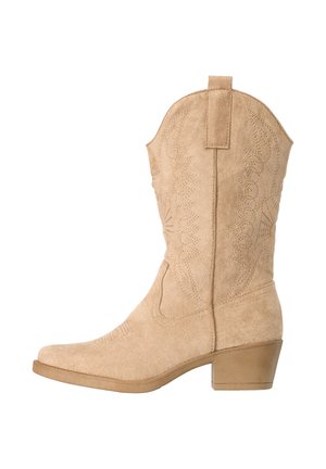 Bota vaquera de ante color beige hasta media pantorrilla con patrones decorativos cosidos y tacón bajo ancho, vista desde el lado exterior.