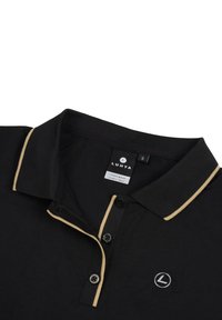 Zwarte polo met een twee-knopenlijst, gouden rand op de kraag en een cirkellogo op de linkerkant van de borst. Label geeft maat S aan.