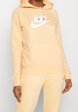 Lichtoranje hoodie gemaakt van zachte stof, met een groot wit Nike-logo, een voorzak en verstelbare trekkoordkap.