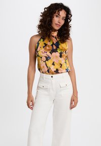 Květinová halter top v žluté, růžové a modré barvě se staženým výstřihem. Doplňkové bílé široké kalhoty s vysokým pasem a kapsami.
