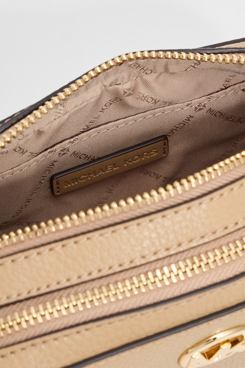 Beige Leder-Handtasche mit Innenausstattung in Gold und einem hellbraunen Futter. Goldfarbene Beschläge und ein Etikett mit der Aufschrift "MICHAEL KORS" sind sichtbar.