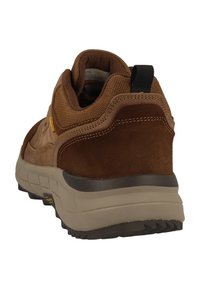 Brauner Sneaker aus Wildleder und Mesh mit einer robusten beigefarbenen Sohle, einem schwarzen Zugband an der Ferse und sichtbaren Nahtdetails.