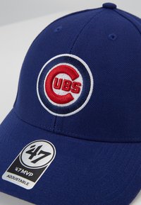 Blaues Baseballcap aus Stoff mit einem gebogenen Schirm. Enthält ein gesticktes Chicago Cubs-Logo in Rot und Weiß. Sichtbares verstellbares Riemenlabel.