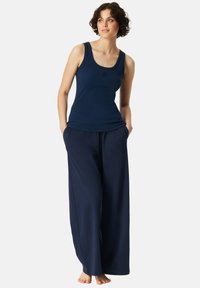 Marineblauwe tanktop met ronde hals, gecombineerd met losse marineblauwe wijde broek. De stof lijkt zacht en geschikt voor casual draag.