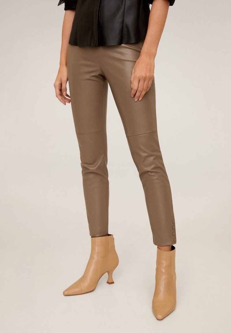 Ruske faux nahkahousut, joissa on istuva muotoilu, sivusaumat ja sileä pinta. yhdistettynä vaaleanbeigeihin nilkkabootseihin.