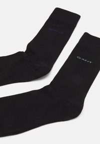 Schwarze Baumwollsocken mit gerippter Textur und Logo-Detail in Blau. Sie verfügen über eine klassische Form und ein knöchelhohes Design.