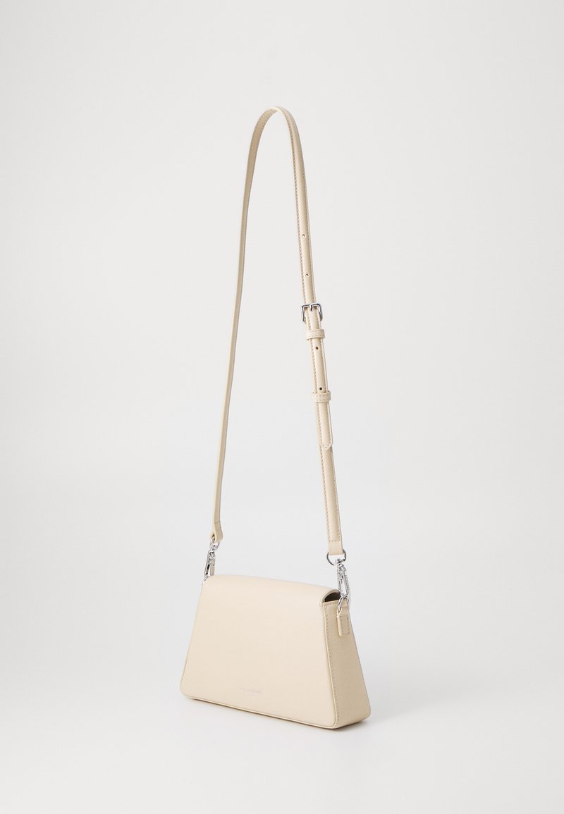 Beige Leder Umhängetasche mit dreieckiger Form, verstellbarem Schulterriemen, silbernen Beschlägen und glatter Textur. Minimalistisches Design ohne Muster.