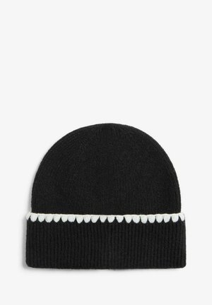 Melna adīta beanie cepure ar teksturētu ribu rakstu un baltu viļņotu akcentu ap apakšējo malu.