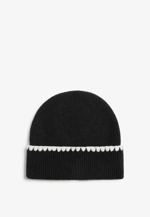 Melna adīta beanie cepure ar teksturētu ribu rakstu un baltu viļņotu akcentu ap apakšējo malu.