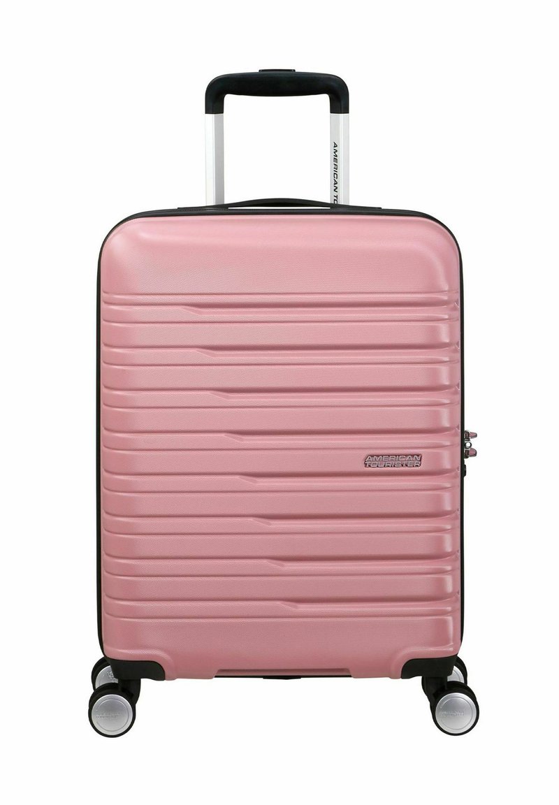 Valigia rigida rosa con linee verticali texturizzate, manico telescopico, quattro ruote e zip nera in accentuazione.