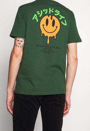 Zelené bavlněné tričko s velkým oranžovým smajlíkovým logem s efektem kapání, zeleným japonským textem a černým potiskem na zádech.