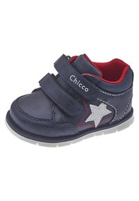 Chaussure en cuir bleu marine pour enfant avec un détail en étoile argentée, doublure en maille rouge et deux bandes Velcro. Semelle en caoutchouc blanc avec un motif texturé.