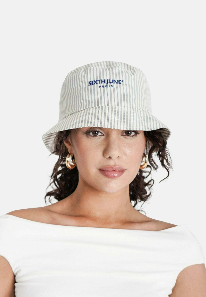 Paskowany kapelusz typu bucket w jasnych kolorach, z niebieskim logo "SIXTHJUNE PARIS" wyraźnie wyeksponowanym. Wykonany z miękkiego materiału, ma okrągły, szeroki rondo.