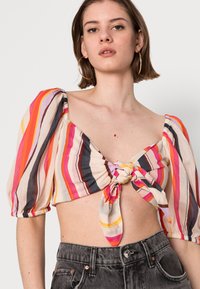 Top cropped às riscas com mangas bufantes, apresentando tons de rosa, laranja e castanho, atado na frente. Feito de um tecido leve.