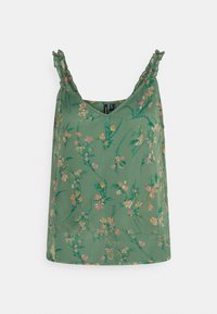 Grüne ärmellose Bluse mit dünnen Rüschenträgern und einem rosa und gelben Blumenmuster auf einem hellen Hintergrund.