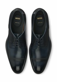 Scarpe da uomo in pelle blu marino con finitura liscia, design con lacci, punta arrotondata e dettagli decorativi perforati lungo le cuciture.