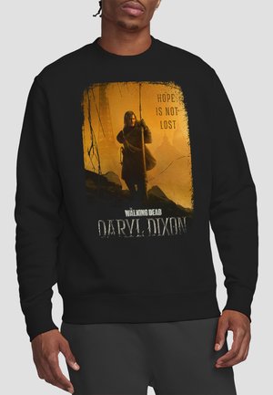 Mann trägt schwarzen Pullover mit Daryl Dixon, der eine Armbrust in einem gelb-orangefarbenen Nebel hält, mit dem Text „Hoffnung ist nicht verloren“ und „The Walking Dead.“