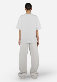 White oversized t-shirt with short sleeves, smooth cotton texture. Paired with light gray, wide-leg pants made of soft fabric.