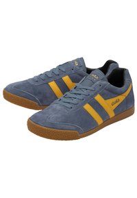 Baskets en daim bleu avec des rayures jaunes, dotées d'une semelle en caoutchouc texturé et de lacets. Logo affiché sur le côté et la languette.