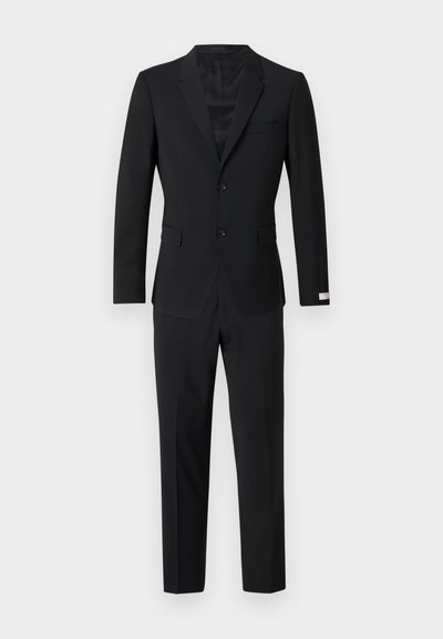 Μαύρο κοστούμι με σακάκι μονόπετο και δύο κουμπιά, παντελόνι στενής γραμμής και γιακάς με γωνία. Λείο ύφασμα και ραμμένη σχ εδίαση.