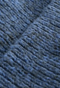 Tessuto a maglia in diverse sfumature di blu, caratterizzato da un motivo testurizzato con fibre spesse e soffici e un aspetto morbido e flessibile.