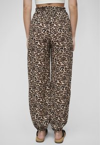 Leopardenmuster-Hosen mit lockerer Passform, ausgestattet mit einem elastischen Bund und gerafften Knöcheln, aus leichtem Material in Braun- und Beigetönen.