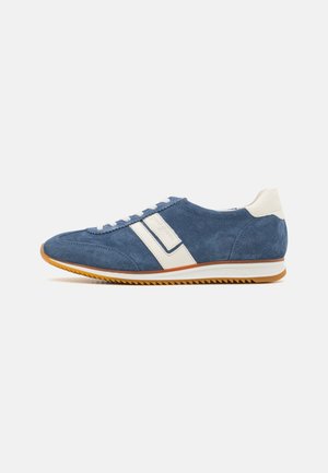 Blaue Wildledersneaker mit weißen Akzenten, runder Zehenpartie und strukturiertem Gummisole. Mit Schnürsenkeln und einem Logo an der Seite.