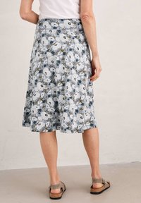 Jupe A-line à motifs floraux en bleu clair avec des fleurs blanches et des accents verts. Fabriquée en tissu doux, elle présente une longueur mi-mollet et une taille élastique.