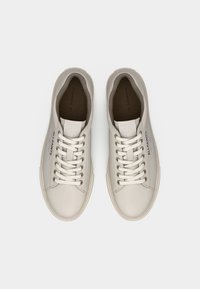 Ζευγάρι μπεζ δερμάτινα αθλητικά παπούτσια με κορδόνια και με την επιγραφή "ALLSAINTS" στο πλάι, φωτογραφημένα από πάνω σε λευκό φόντο.