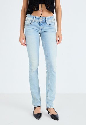 Jeans azul claro, de pierna recta y con un acabado desgastado, diseño de cinco bolsillos y costuras claras. Llevados con un top negro corto y tacones negros.
