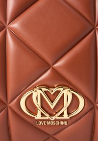 Brun quiltad konstläderväska med en gyllene "Love Moschino"-logotyp. Ytan har ett diamantmönster och en slät textur.