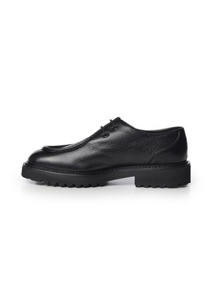Zapato negro de cuero con cordones, puntera redondeada y suela gruesa con dibujo, mostrado de perfil sobre un fondo blanco.