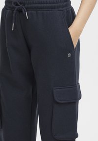 Donkerblauwe joggerbroeken van zachte stof, met een elastische tailleband, zijzakken en een cargozak met klepdetail.