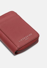 Rood leren portemonnee met een textuurafwerking, met kaartsleuven en een ritscompartiment. Gekenmerkt met "LIEBESKIND BERLIN" in zilveren letters.