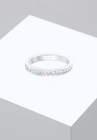 925 ezüst gyűrű, amelyen elöl világos, téglalap alakú kövek sorakoznak. Simány bandás, fényes felülettel.