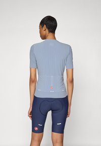 Blaues kurzärmliges Fahrradtrikot aus strukturiertem Stoff mit Rückentaschen, kombiniert mit dunkeln marineblauen Shorts mit gepolstertem Design und reflektierenden Akzenten.