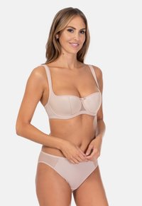 Biustonosz i majtki w kolorze nude; posiadają gładki materiał, szerokie ramiączka oraz siateczkowy panel z akcentem w postaci kokardy na środku biustonosza.