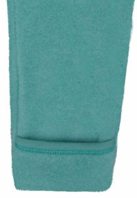 Teal fleece-stof met een zachte textuur en een geribbelde zoomafwerking. De stof heeft een gladde afwerking, wat de warmte en het comfort verhoogt.