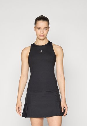 Black ribbed tank top with a fitted design, round neckline, and logo accent. Paired with a pleated black skirt, showcasing a sporty look.