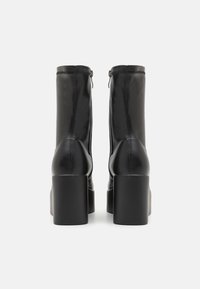 Schwarze Kunstleder-Ankle-Boots mit einem robusten Blockabsatz, Reißverschlussteil am Rücken und genähten Akzenten an den Seiten.
