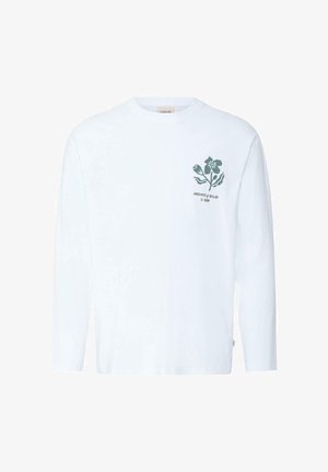 Λευκό πουκάμισο με μακριά μανίκια, με πράσινο λουλουδάτο σχέδιο και το κείμενο "ARCHIVE of SOLID © 1999" στο αριστερό στήθος.