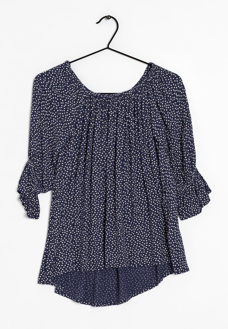 Granatowa bluzka w białe kropki, z elastycznym dekoltem, 3/4 rękawami z falbankami i asymetrycznym hemem. Wykonana z lekkiego materiału.