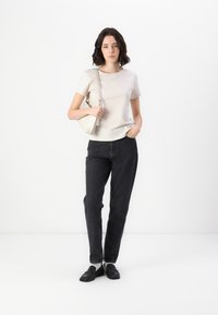 Beige cotton t-shirt with a rounded neckline, paired with dark gray straight-leg jeans and black loafers. Accessory includes a light tote bag.