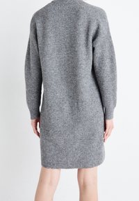 Abito a maglia grigio a coste con maniche lunghe, scollatura rotonda e orlo fino al ginocchio, che mette in risalto una texture morbida e una vestibilità rilassata.