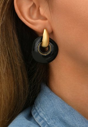 Boucles d'oreilles noires en forme de cercle avec un accent doré. La pièce dorée a une forme pointue, contrastant avec la finition noire brillante de la partie circulaire.
