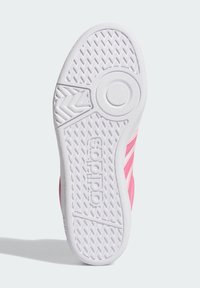 Sole in gomma bianca di una sneaker Adidas con motivi di battistrada circolari e a zigzag, che mostra parte della tomaia rosa con strisce.