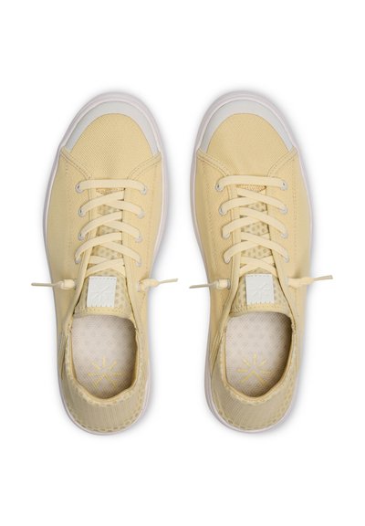 Paire de baskets lacées jaune clair avec des embouts en caoutchouc blanc et des dessus en mesh doux, vues de dessus sur un fond blanc.