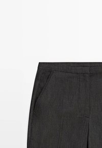Pantalon gris foncé sur mesure avec poches latérales et ceinture droite, présenté sur un fond blanc.